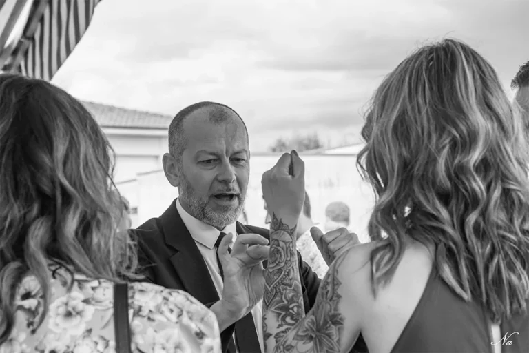 Photo en noir et blanc de Lioz magicien à Metz parlant à deux femmes en extérieur.